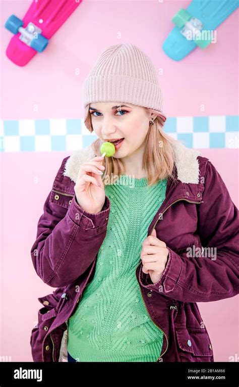 Young Woman Wearing Purple Jacket And Green Sweater Posing Over Pink