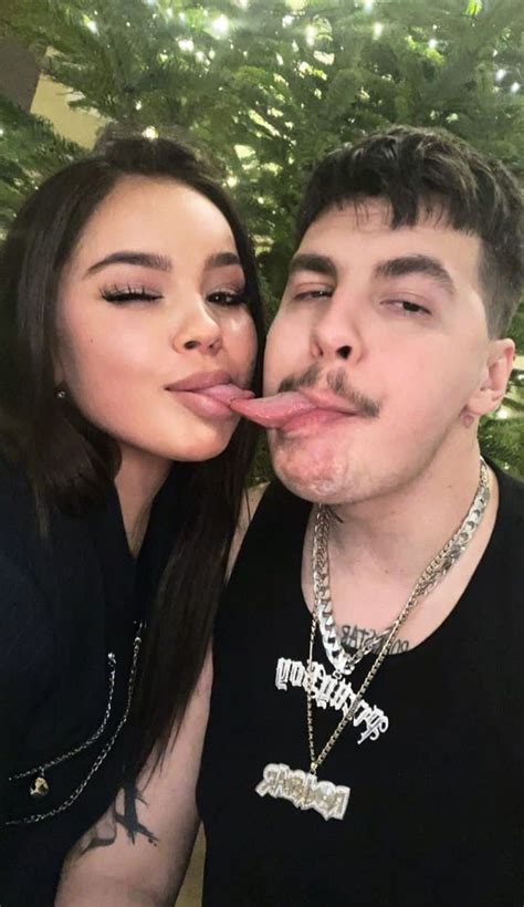 A Man And Woman Sticking Their Tongues Out To Each Other While Posing