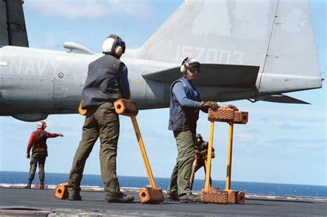 Flight Deck Crewmen Stand By With Wheel Chocks Aboard The Aircraft