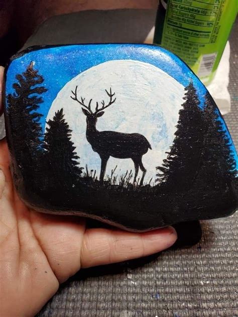 A Hand Holding A Painted Rock With A Deer On It