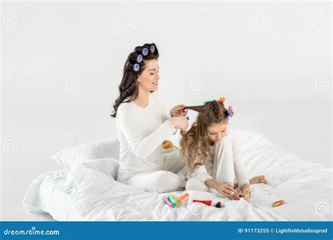 Mother Curling Hair To Daughter Applying Nail Polish While Sitting On Bed Stock Image Image Of