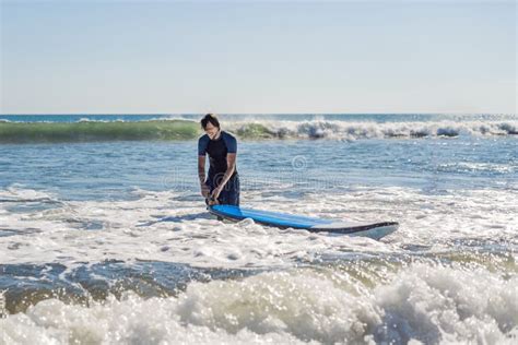 Young Man Beginner Surfer Learns To Surf On A Sea Foam On The Bali