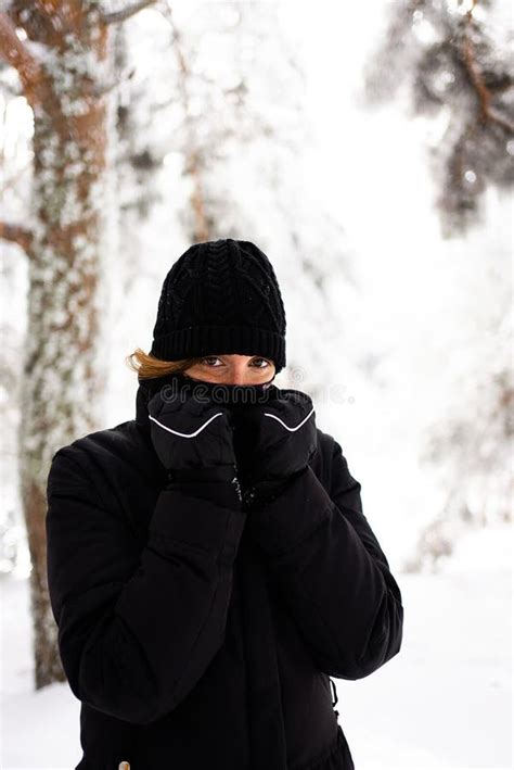 A Woman Bundled Up In A Thick Black Coat Braving The Cold Weather With