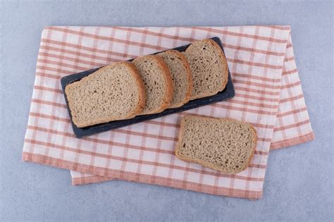 Free Photo Tray Of Sliced Brown Bread On A Folded Towel On Marble Surface