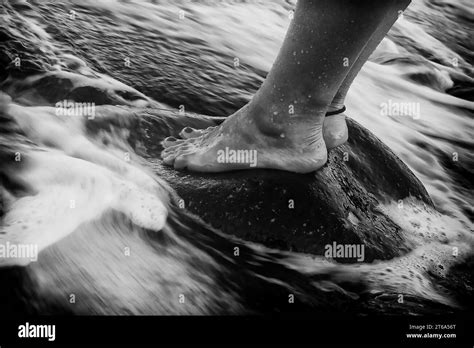 Black And White Photograph Of A Person Standing In The Surf With Their