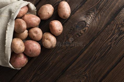 Patatas Frescas En Un Bolso Viejo De La Lona De Lino En Un Fondo Oscuro