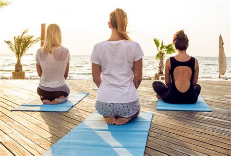 Gruppo Di Giovani Femmine Che Praticano Yoga Sulla Spiaggia Durante L