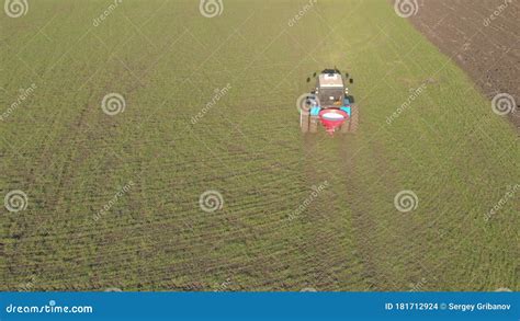 Tractor Spreading Artificial Fertilizers In Green Field Farmer