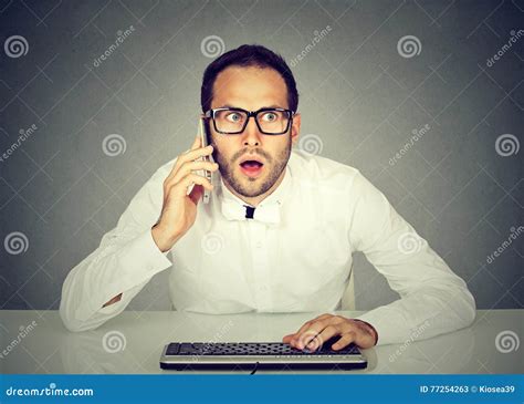 Shocked Businessman Talking On Phone While Using Computer Stock Image