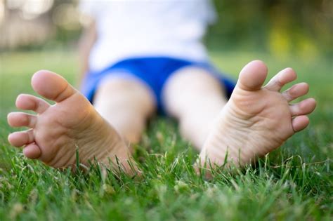 Premium Photo | Barefoot feet closeup a child sitting on the grass in ...