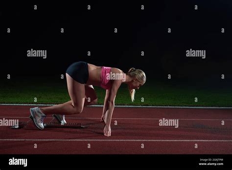 Woman Sprinter Leaving Starting Blocks On The Athletic Track Side View