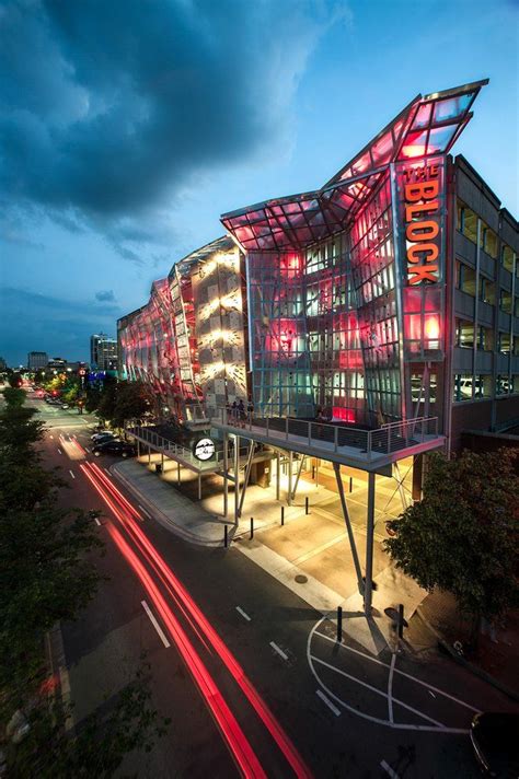 an aerial view of the exterior of a modern building at night with red lights on it