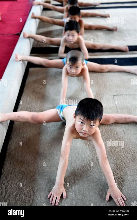 Young Chinese boys bend their bodies and do the splits on the floor to practice gymnastics at a ...