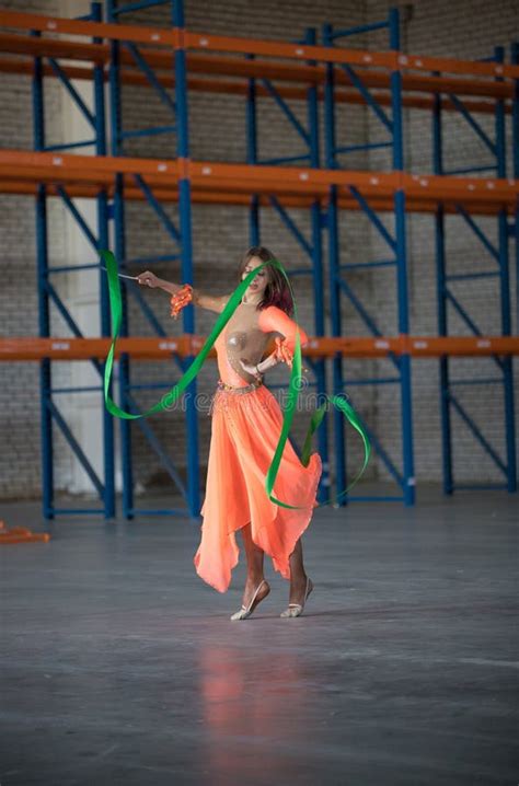 Dança Da Jovem Mulher a Fita Ginástica Nas Mãos No Armazém Imagem