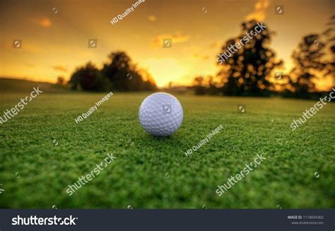 Golf Ball On Tee Ready To Be Shot On The Green Golf Course On Sunset