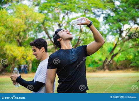 Two Men Drinking Water From Bottle After Fitness Sport Exercise Stock