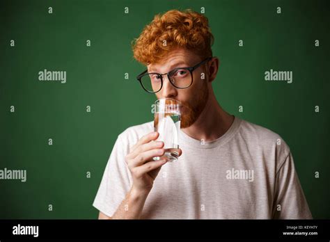 Handsome Curly Readhead Bearded Man In Glasses Drinking Water Looking