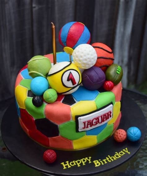 A Birthday Cake Decorated With Colorful Balls And Sports Equipment