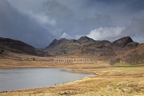 Craggy Hills Beyond Lake During Daytime — Tranquility Travel