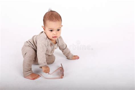 Curious Baby Boy In Cream Clothes Playing With Sunglasses Stock Image