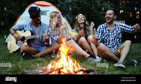 Group Of Friends Camping And Sitting Around Camp Fire Stock Photo Alamy