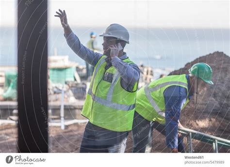 Lächelnder Bauarbeiter im Gespräch mit Mann auf der Baustelle ein