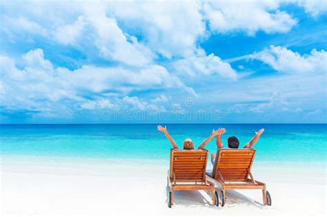 Romantic Couple On Deckchair Relaxing Enjoying Sunset On The Beach