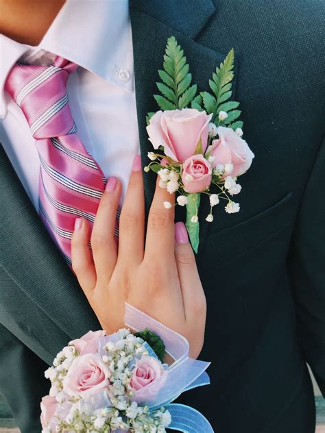 A Close Up Of A Person Wearing A Suit And Tie With Flowers On His Lapel