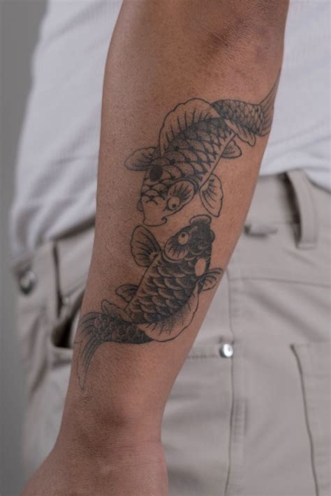 A Man With A Fish Tattoo On His Arm