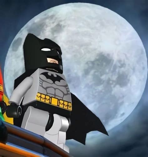 A Lego Batman Standing On Top Of A Roof In Front Of The Moon And Clouds