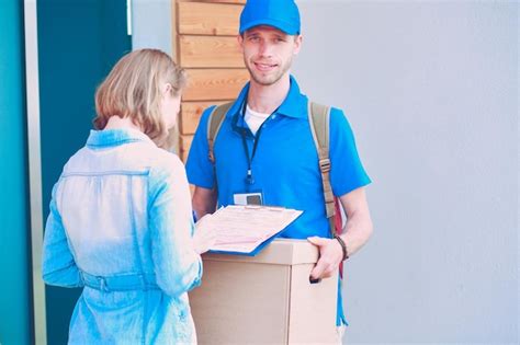 Premium Photo Smiling Delivery Man In Blue Uniform Delivering Parcel