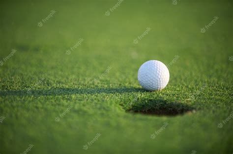 Premium Photo | White golf ball on green field close up