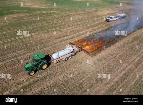 A Tractor Pulls A Propane Burner To Burn Weeds In An Hay Field After