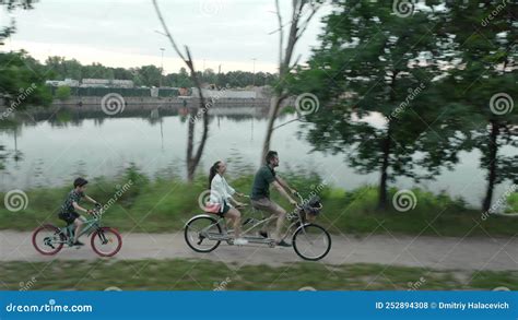 Married Couple With A Child Rides A Two Person Tandem Bike Along The