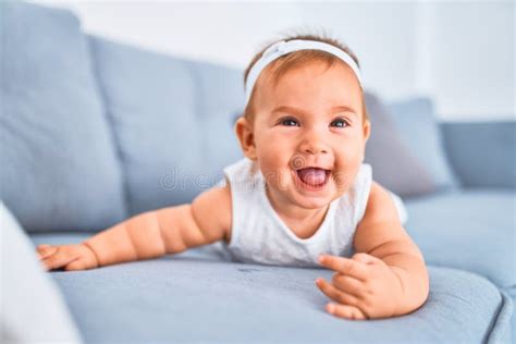 Adorable Baby Lying Down On The Sofa Smiling Happy At Home Stock Photo