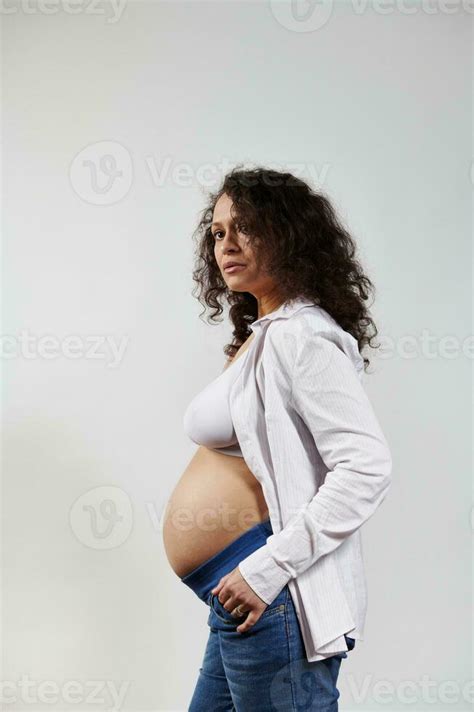 Vertical Portrait Of Curly Haired Pregnant Woman Posing Bare Belly On