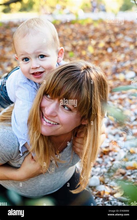 Femme Portant Son Fils Sur Le Dos Et Souriant Banque De Photographies