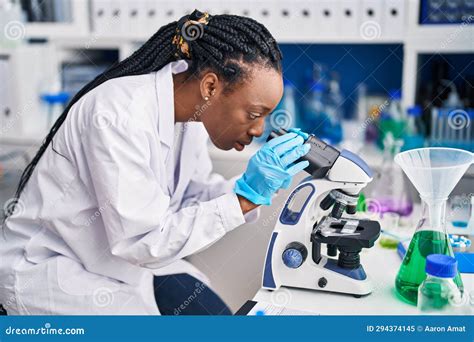 African American Woman Scientist Using Microscope At Laboratory Stock