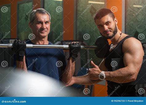 Homem Superior Que Exercita O Instrutor Pessoal No Gym Imagem De