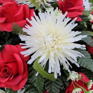 A Headstone Saddle With Red Roses And Cream Mum Grave Flowers For