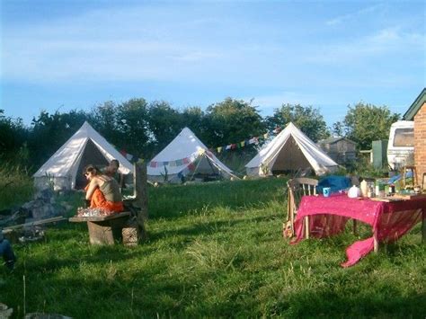 Several Tents Are Set Up In The Grass Near A Picnic Table And Chairs