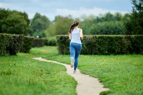 Female Runner Exercising In Public Park In Summer Back View Stock