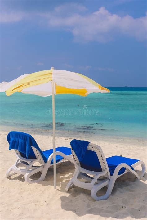 Two Blue Plastic Chaise Lounges Under Yellow Umbrella On The Local