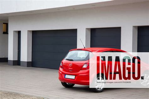 An Opel Corsa Parked In Front Of One Of Several Garages With Black