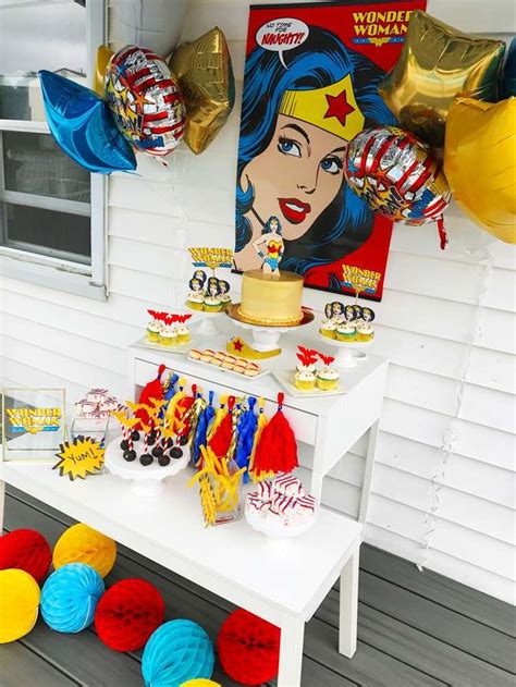 The Table Is Set Up With Decorations And Balloons For Wonder Woman