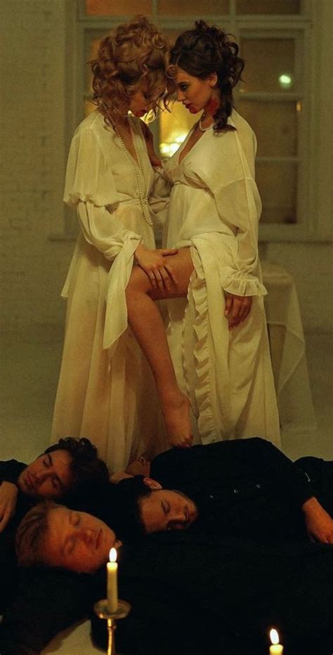 Two Women In White Robes Sitting On The Ground With Candles Around Them