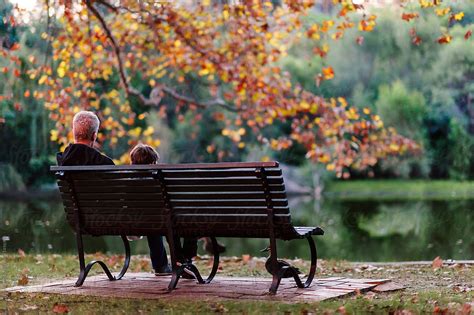 Father And Son Sitting On A Park Bench After Sunset In Autumn By