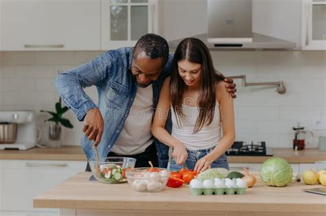 A Happy Interracial Couple Preparing Food In The Kitchen An African