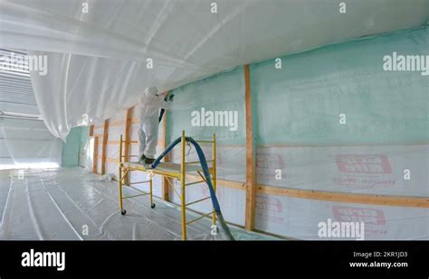 Man In Respirator And Tyvek Suit Sprays Closed Cell Foam Insulation On