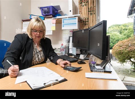 A Business Administrator Office Manager By Her Desk In A Busy Office